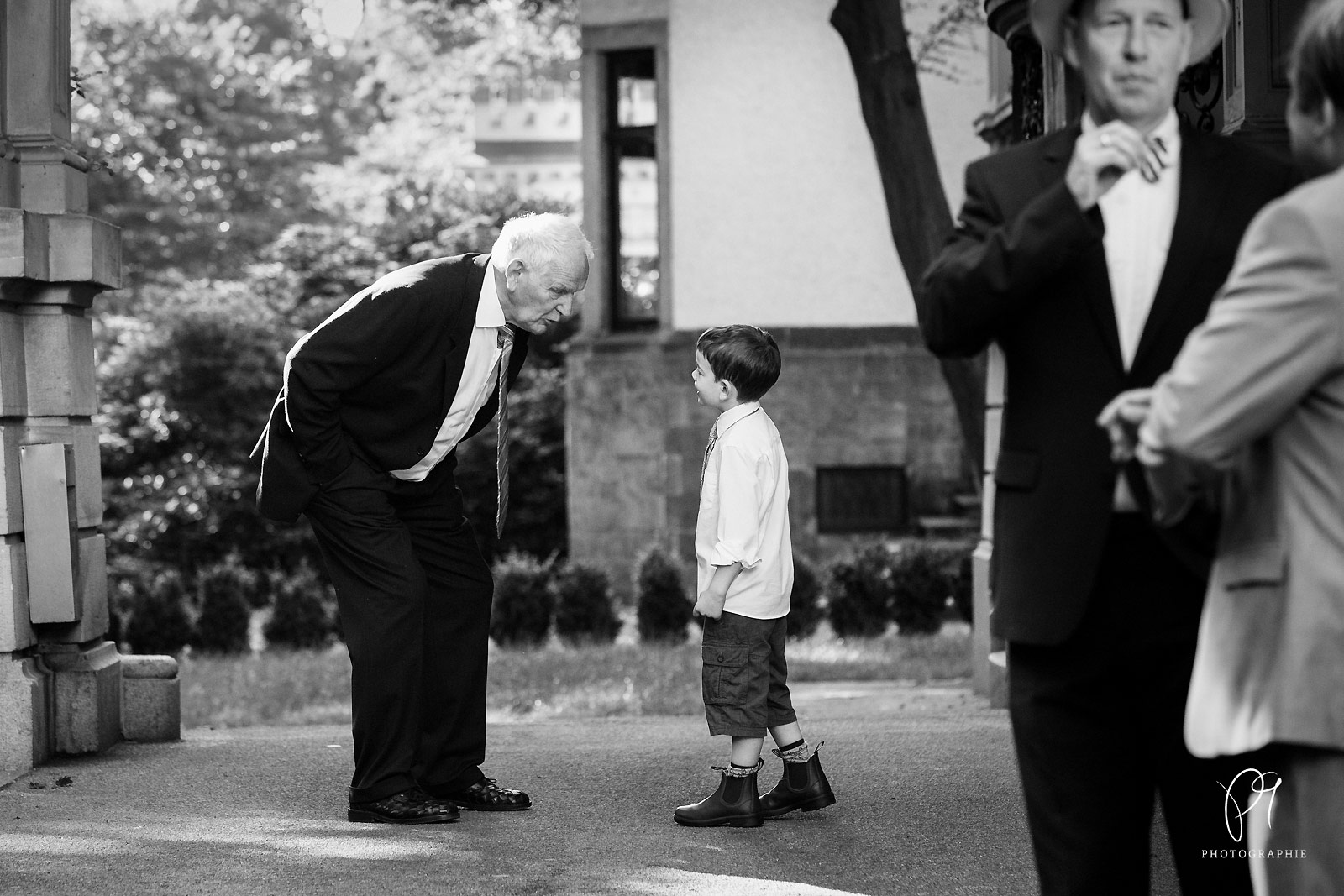 Eine Hochzeit ist immer ein großes Familienfest. Auf diesem Foto einer Hochzeitsreportage aus Bremen sieht man ein Opa in einer Unterhaltung mit seinem Enkel.
