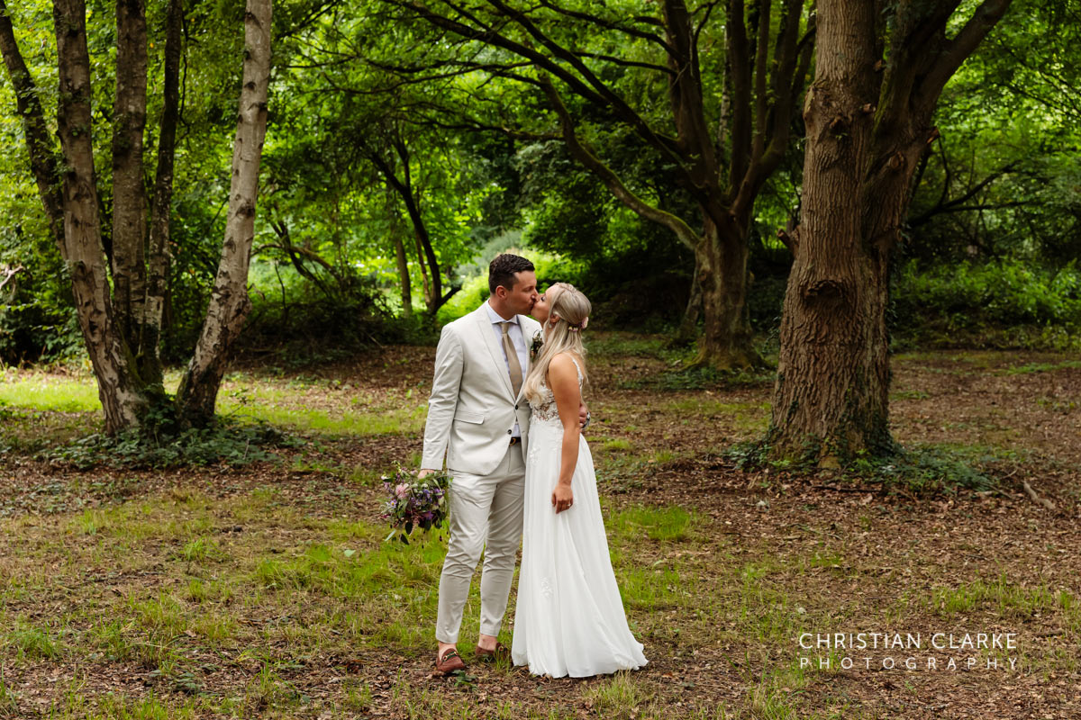 Das frischvermählte Brautpaar küsst sich in einem märchenhaften Wald