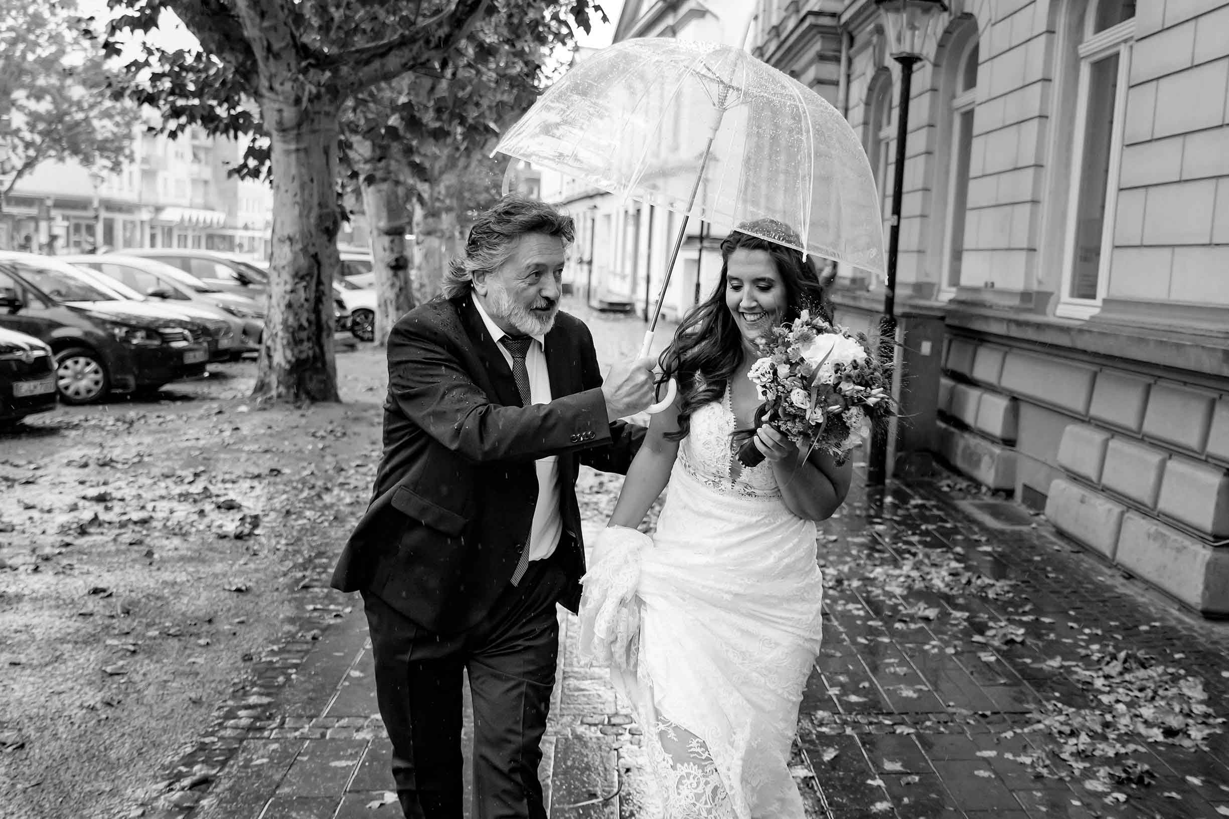Hochzeit Braut und Brautvater mit Regenschirm