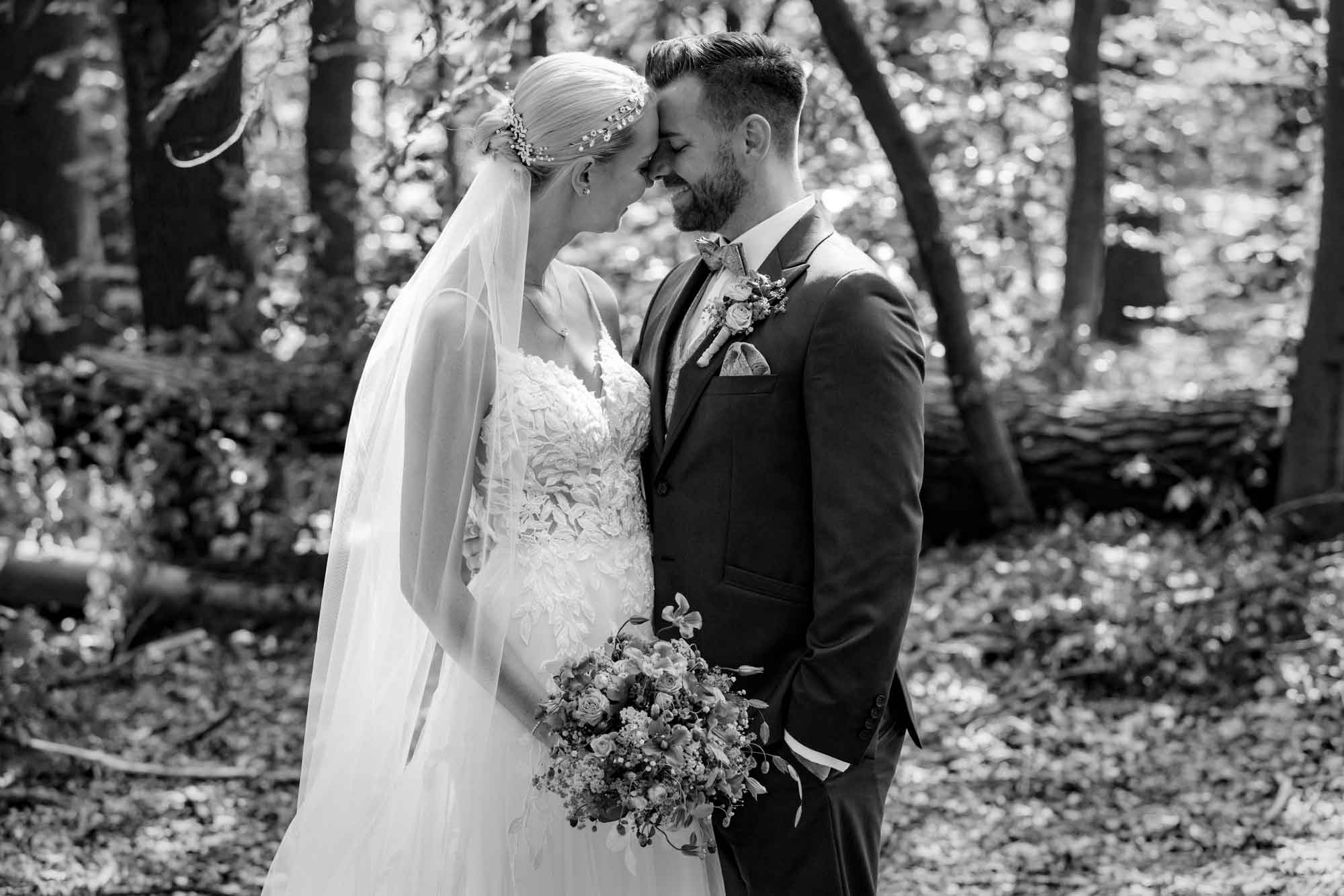 Ein Brautpaar posiert in einem Wald für Hochzeitsfotos