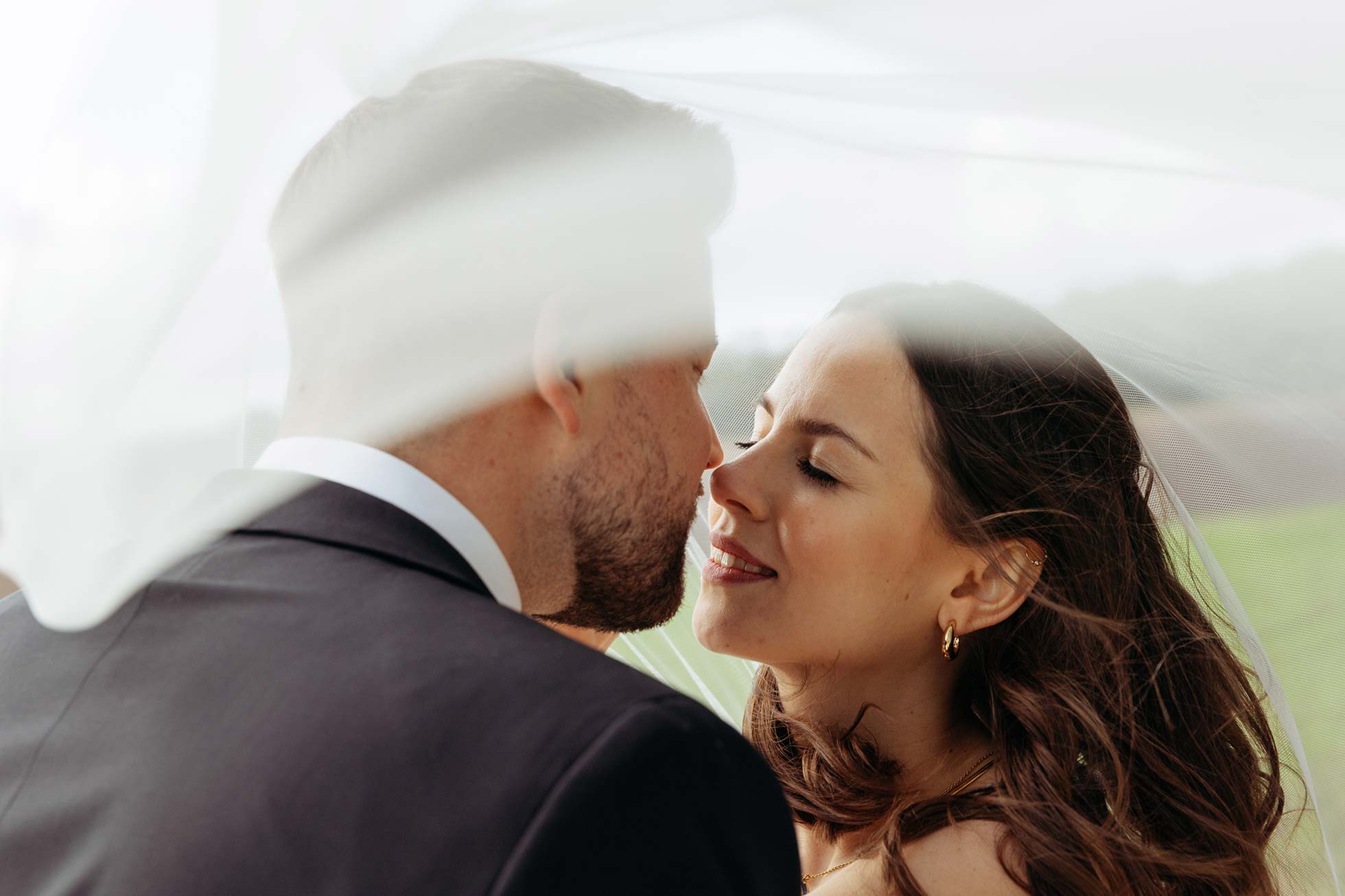 Kurz vor einem Kuss. Ein Hochzeitsfoto unter dem Schleier der Braut.