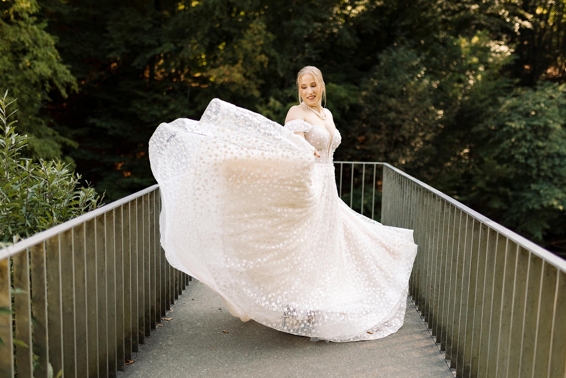 Die Braut wirft ihr Brautkleid in die Höhe. Dieses Hochzeitsfoto wurde in Solingen Müngsten aufgenommen und ist eine Teil einer Hochzeitsreportage.